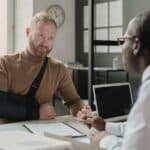 Portrait of man with hand in sling talking to insurance broker after workplace injury. Concept of is SSDI retroactive